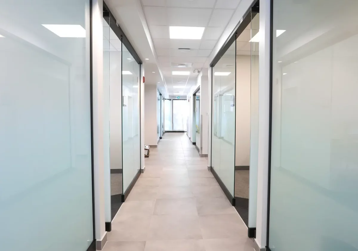 Corridor moderne avec bureaux vitrés et éclairage encastré – aménagement Caisse Desjardins Saint-Félix-de-Valois
