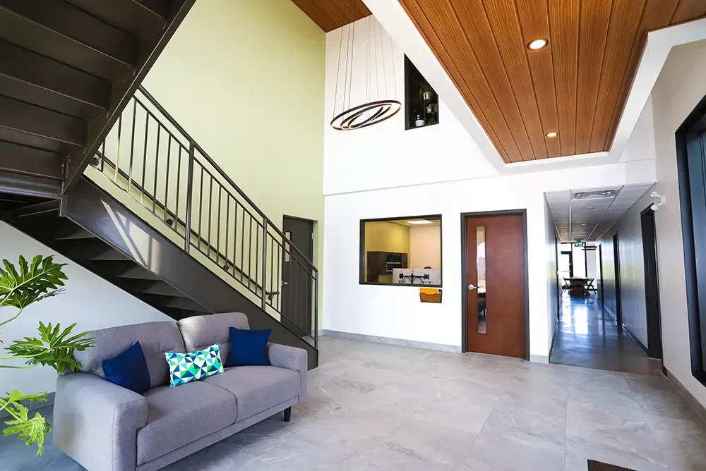 Hall d'entrée double hauteur avec escalier d'acier, plafond de bois et luminaire suspendu – projet agricole BGC