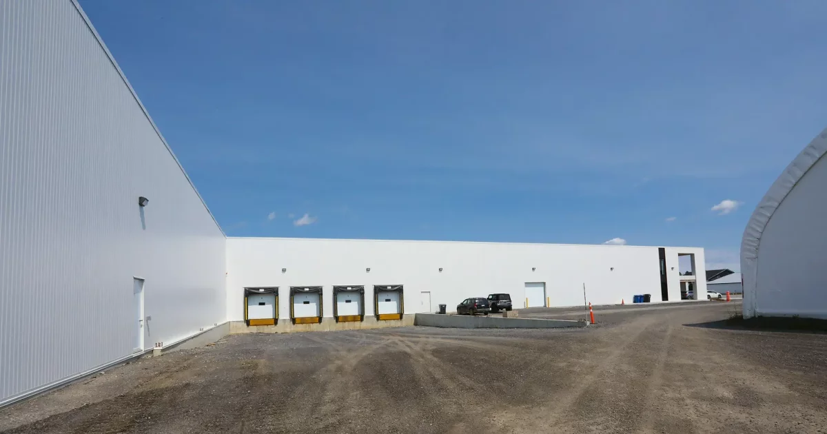Façade extérieure avec quais de chargement jaunes et bâtiment en acier blanc – entrepôt agricole Lanaudière