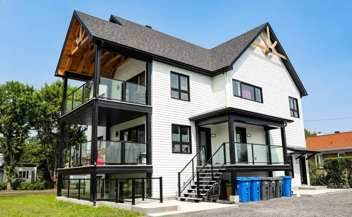 Vue arrière du triplex blanc avec balcons superposés et charpente de bois décorative – projet Louis Bérard par BGC