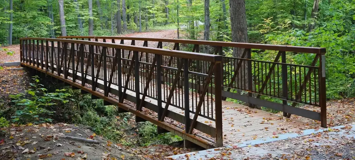 Pont piétonnier en acier avec garde-corps traversant le boisé – Parc du Grand-Coteau Mascouche par BGC