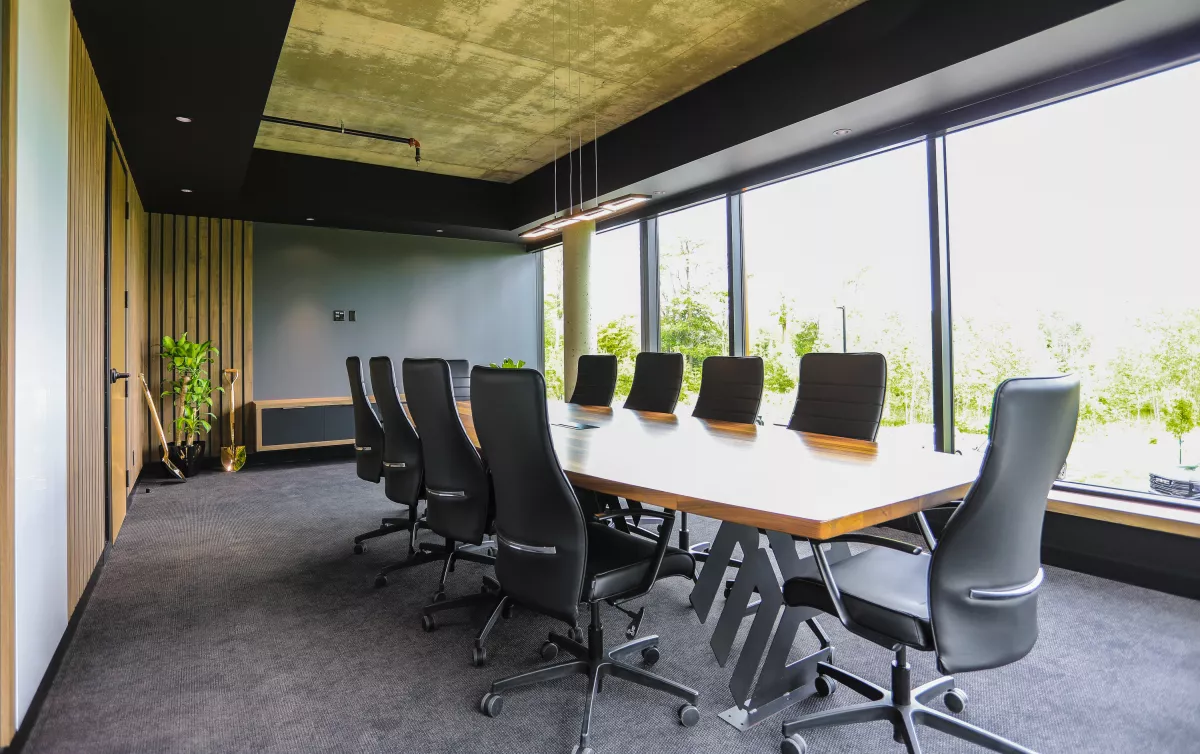 Salle de conférence avec table en bois live-edge, chaises grises et lattes murales