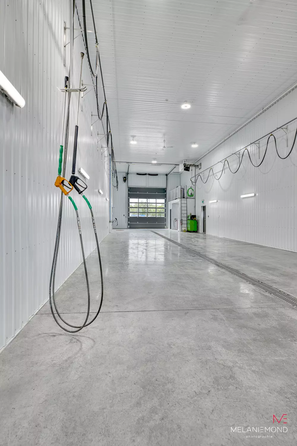 Intérieur de la baie de lavage avec boyaux de carburant et plancher de béton – garage Épandage YFL Joliette par BGC