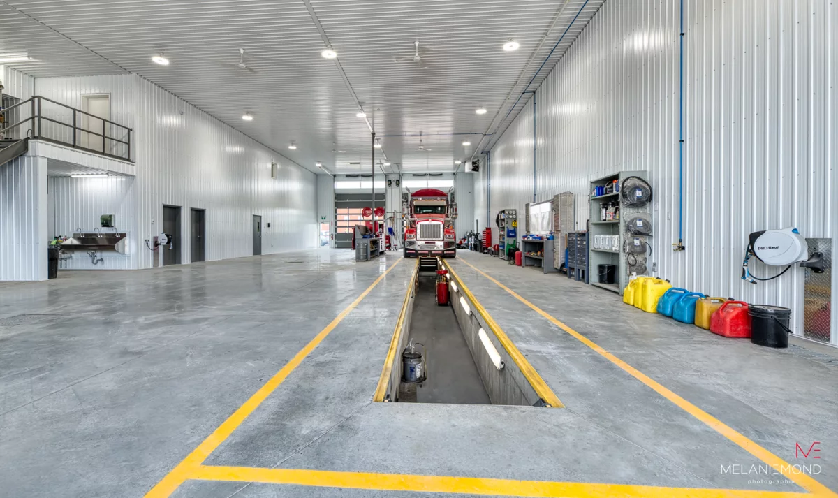 Garage avec fosse de mécanique, camion rouge et équipements – bâtiment industriel Épandage YFL Joliette par BGC
