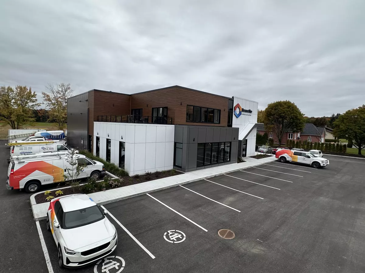 Vue du stationnement et façade du bâtiment Bessette avec véhicules de service – projet commercial Lanaudière par BGC
