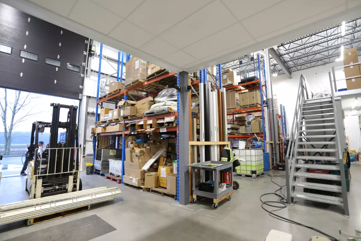 Zone d'entrepôt avec chariot élévateur, rayonnages et escalier d'acier – construction commerciale Bessette par BGC