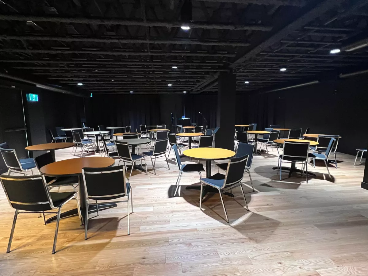 Salle polyvalente de la Maison de la musique avec tables bistro et plancher de bois