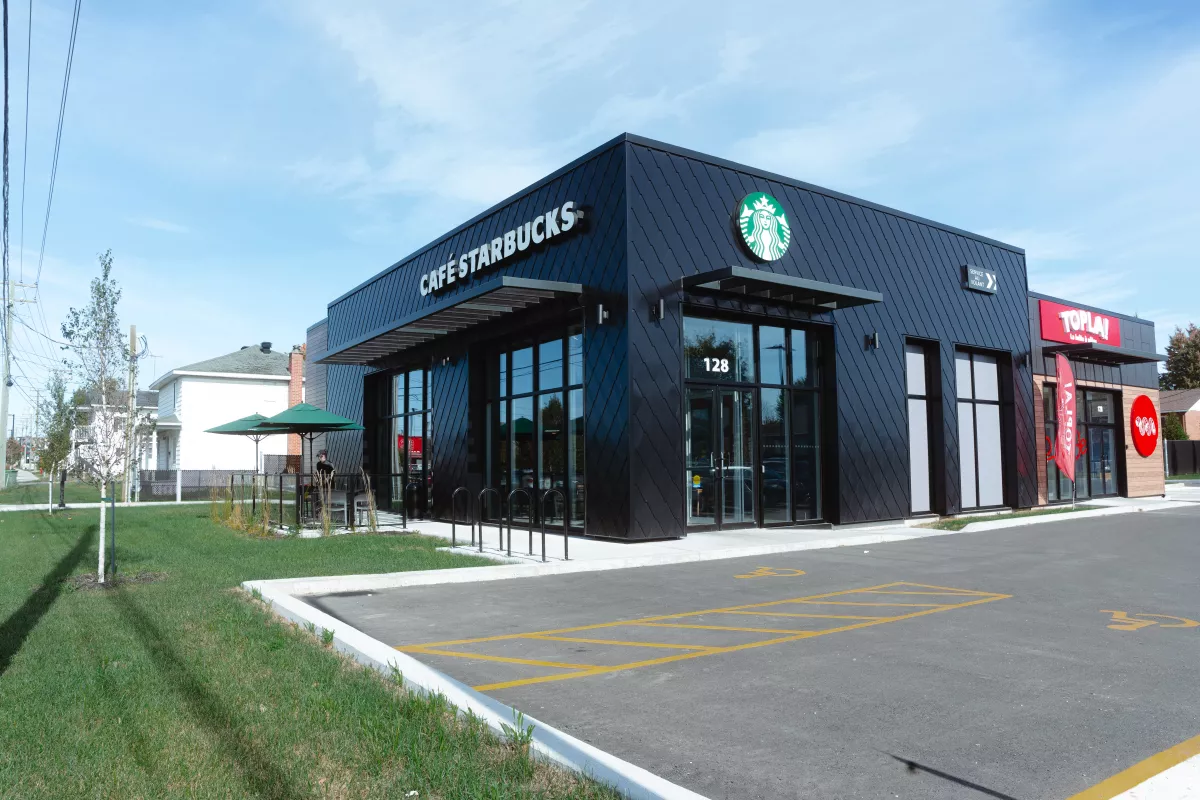 Entrée du Café Starbucks avec logo, auvent métallique et revêtement en acier noir