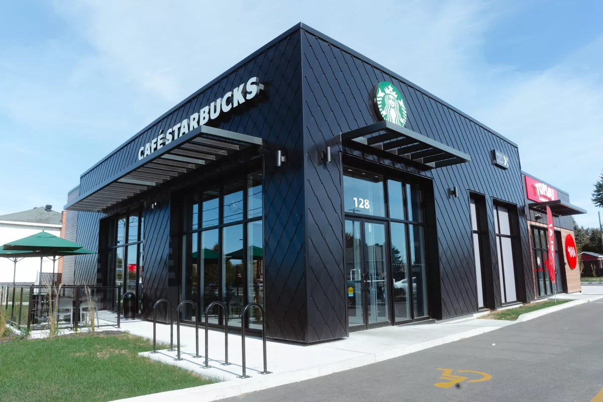 Façade frontale du Starbucks avec portes vitrées et enseigne lumineuse