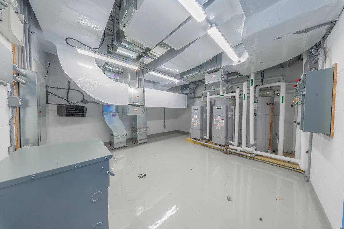 Salle mécanique avec conduits de ventilation, chauffe-eau et panneaux électriques