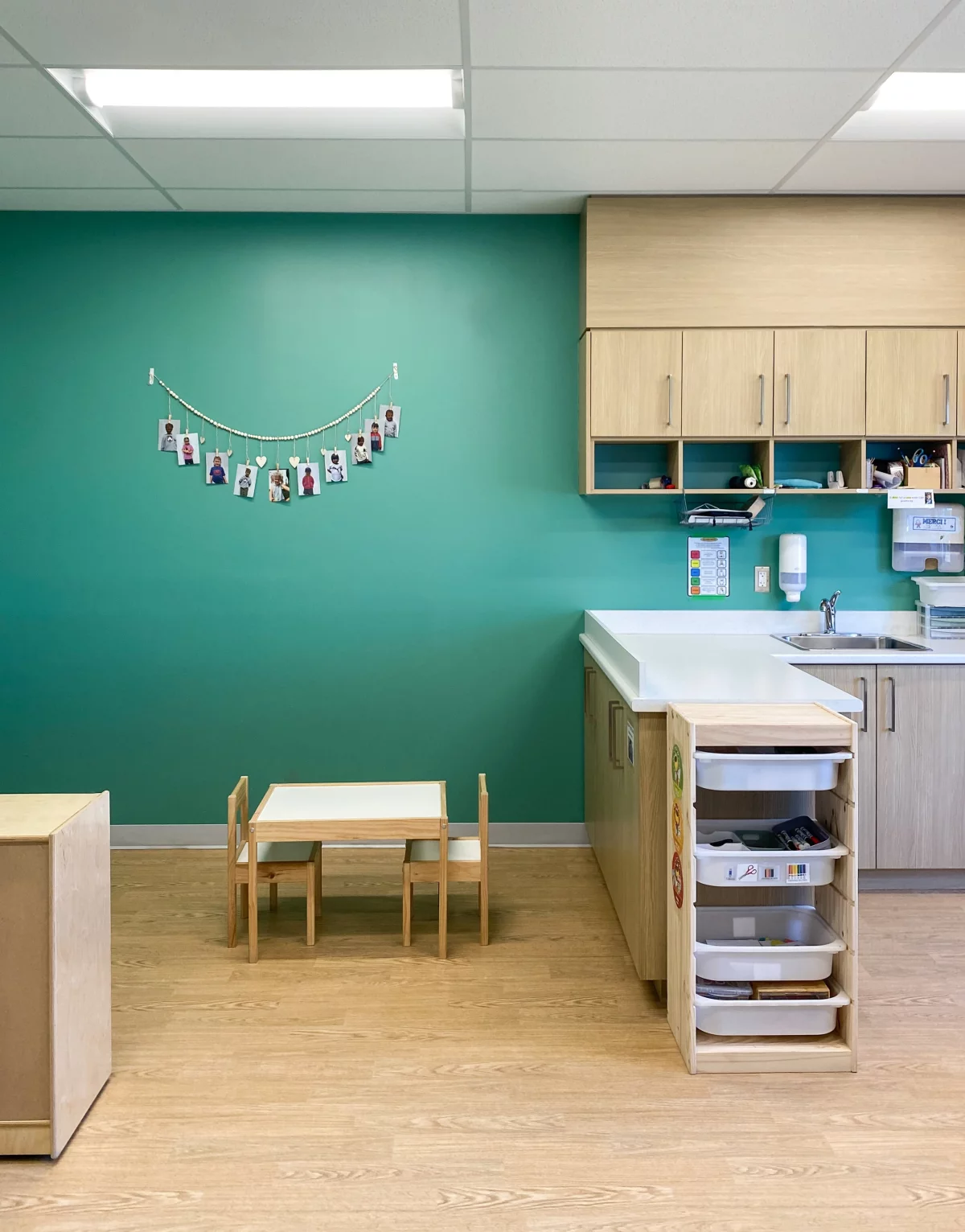 Salle de groupe avec mur turquoise, armoires en bois et coin activités – CPE Joliette