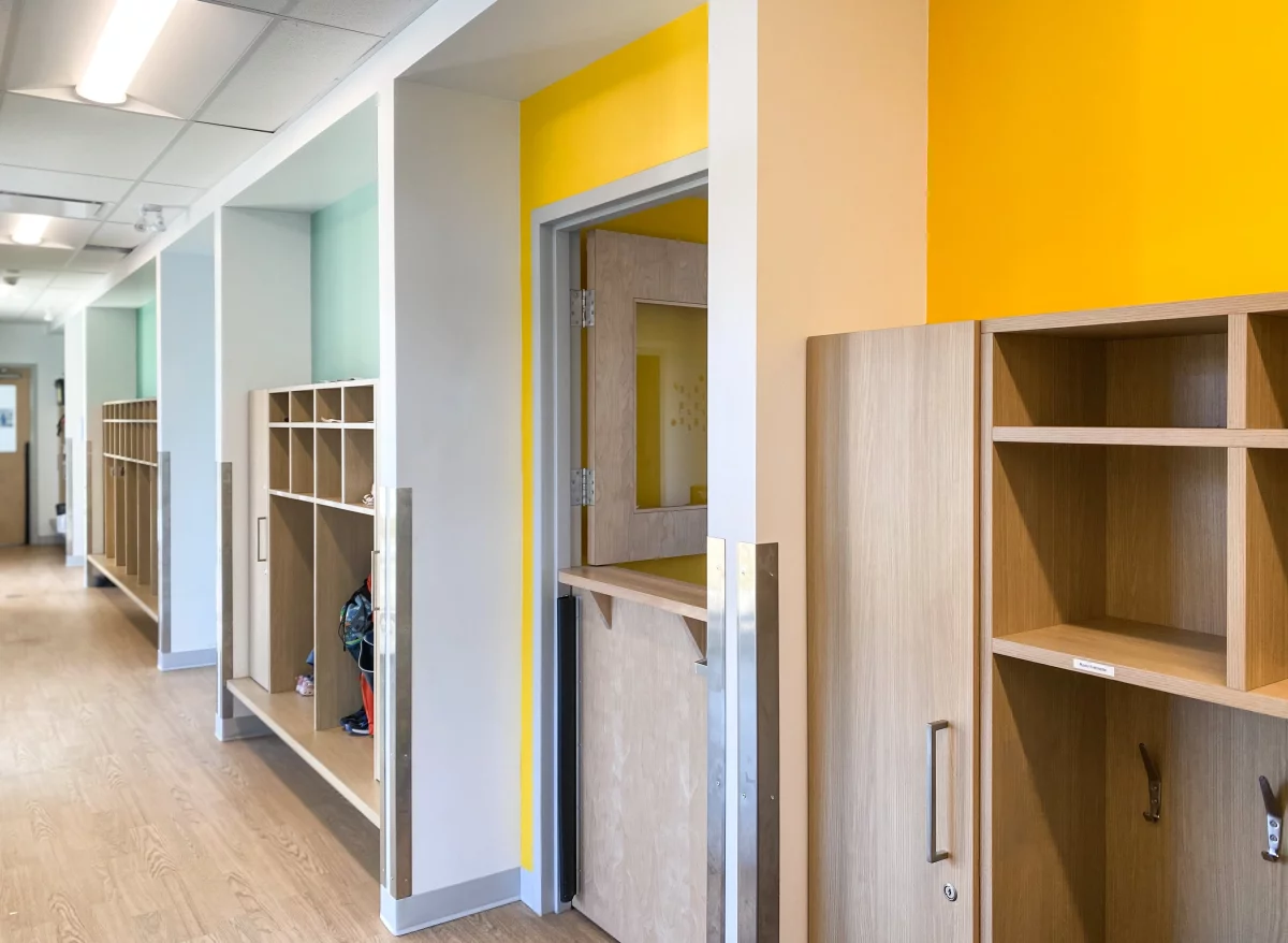 Corridor avec casiers intégrés en bois et murs colorés – construction institutionnelle BGC