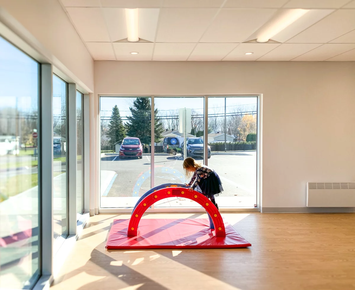 Salle de jeux lumineuse avec grandes fenêtres et équipements de motricité