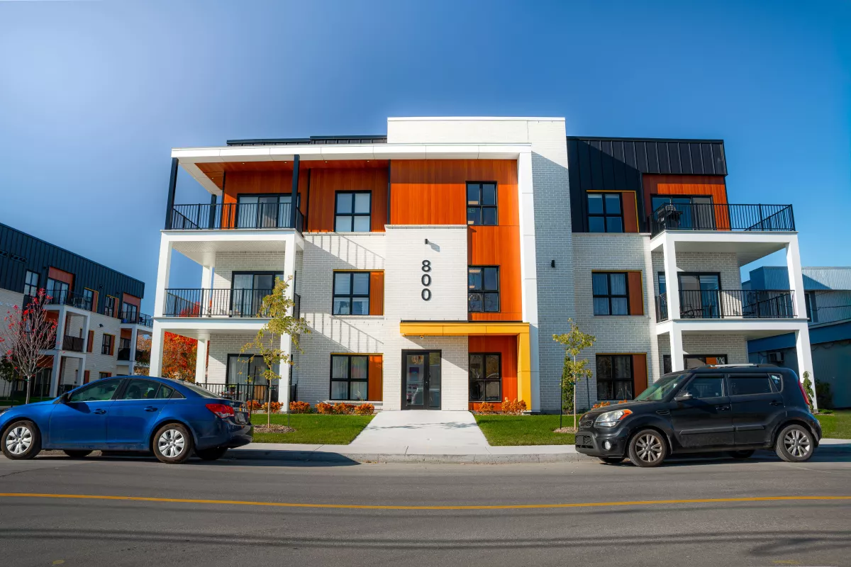 Façade du 800 avec entrée jaune, briques blanches et accents de bois – multi-résidentiel BGC