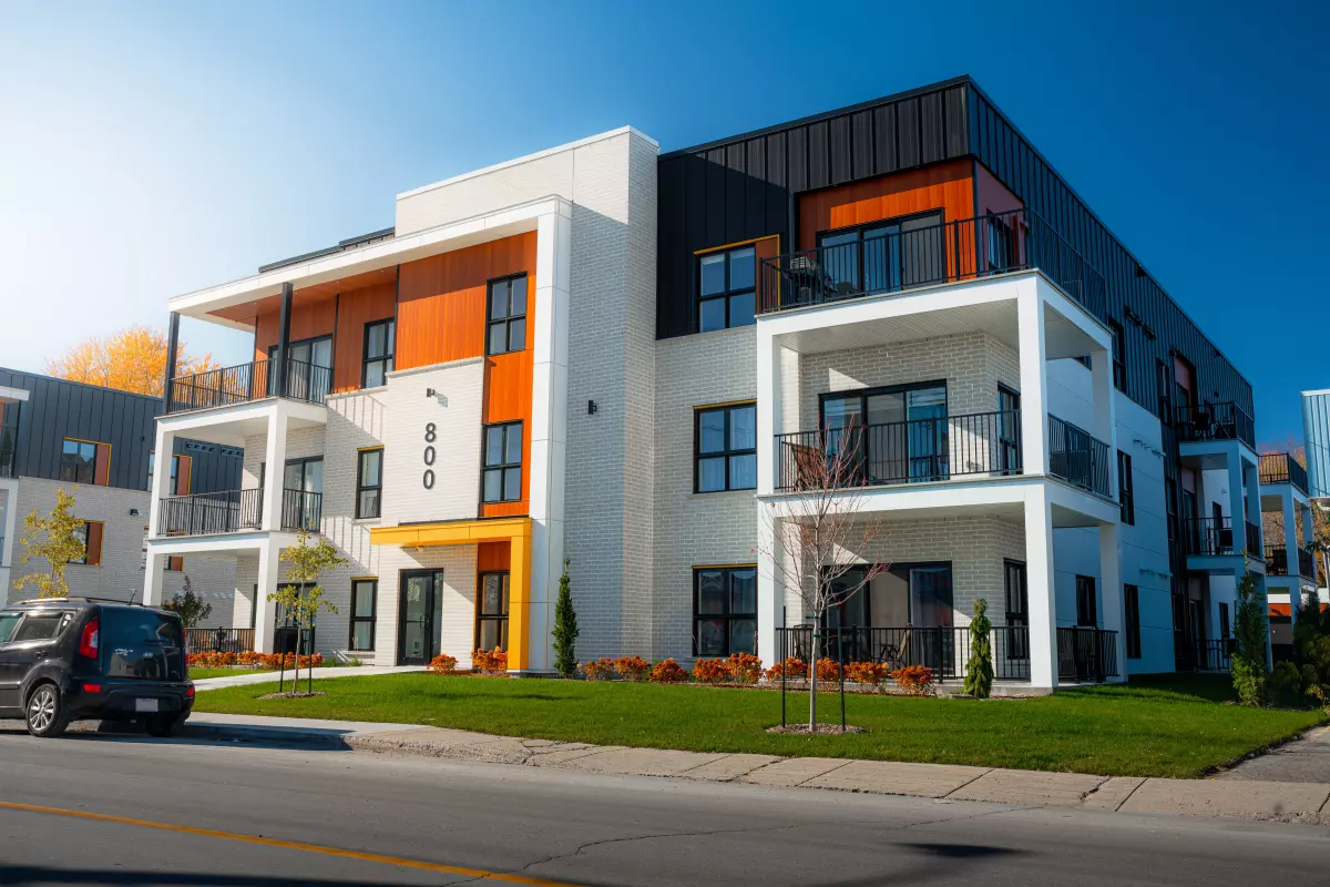 Bâtiment multi-logements avec balcons, revêtement mixte blanc et noir – construction neuve BGC