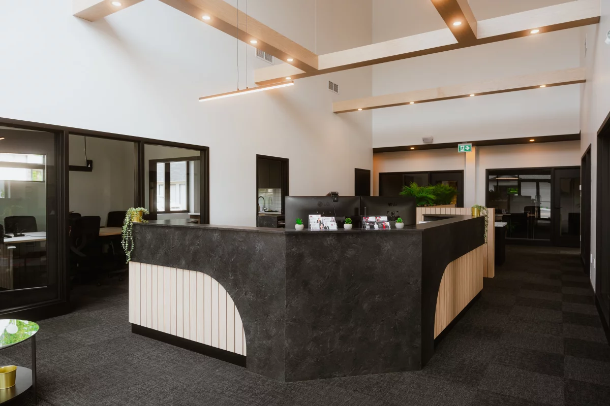 Réception avec comptoir en pierre foncée et détail en bois – construction commercial BGC