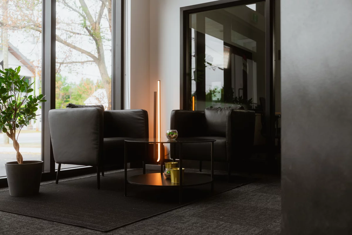 Salon d'attente avec fauteuils en cuir noir, lampe LED et grandes fenêtres